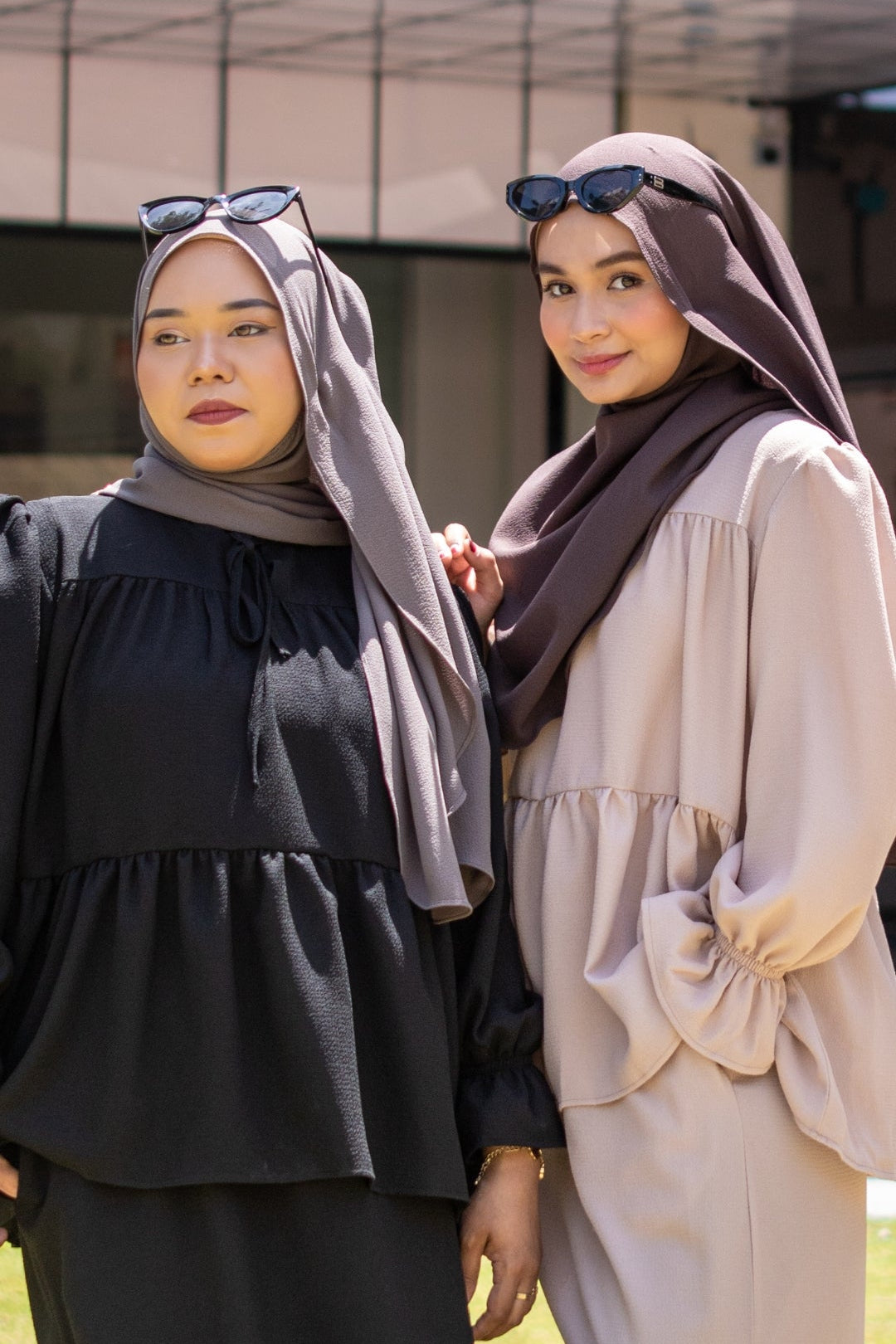 Two women wearing hijabs standing outdoors with a blurred background