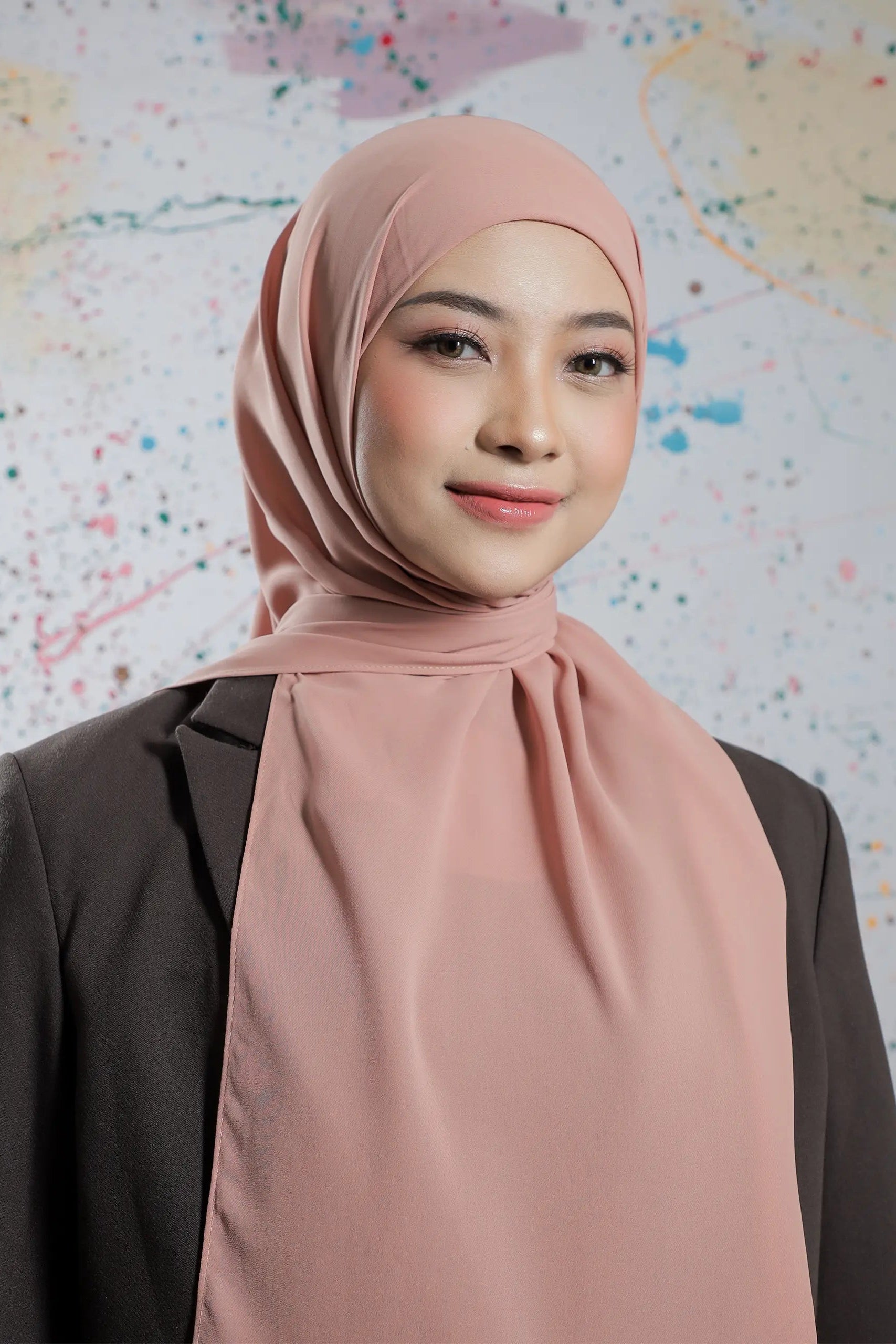 Woman wearing a pink hijab against a colorful abstract background