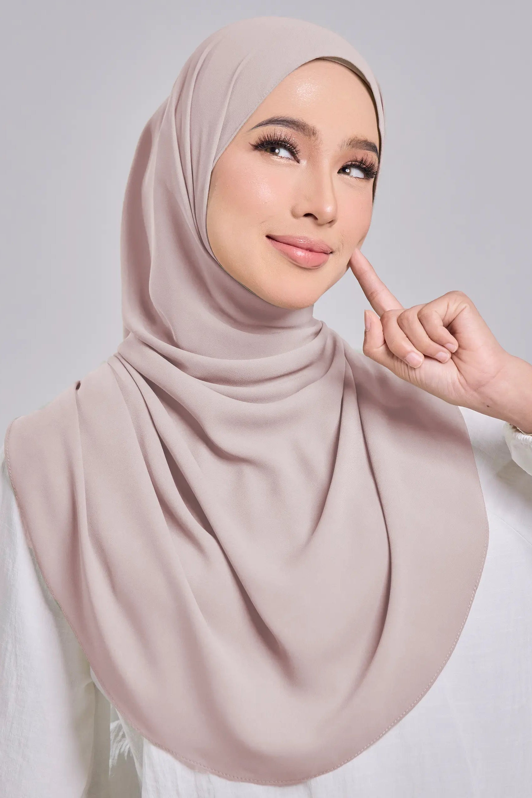 Woman wearing a beige hijab with a neutral background