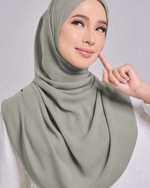 Woman wearing a green hijab against a gray background