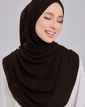 Woman wearing a dark brown hijab and white shirt on a gray background