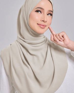 Woman wearing a beige hijab with a neutral background