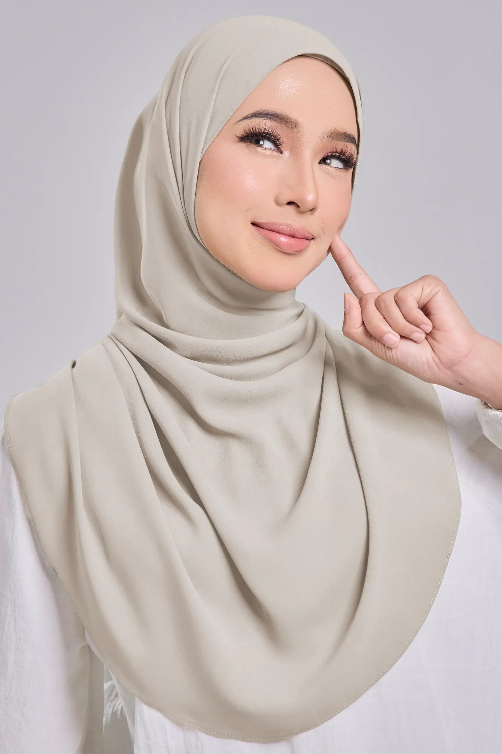 Woman wearing a beige hijab with a neutral background