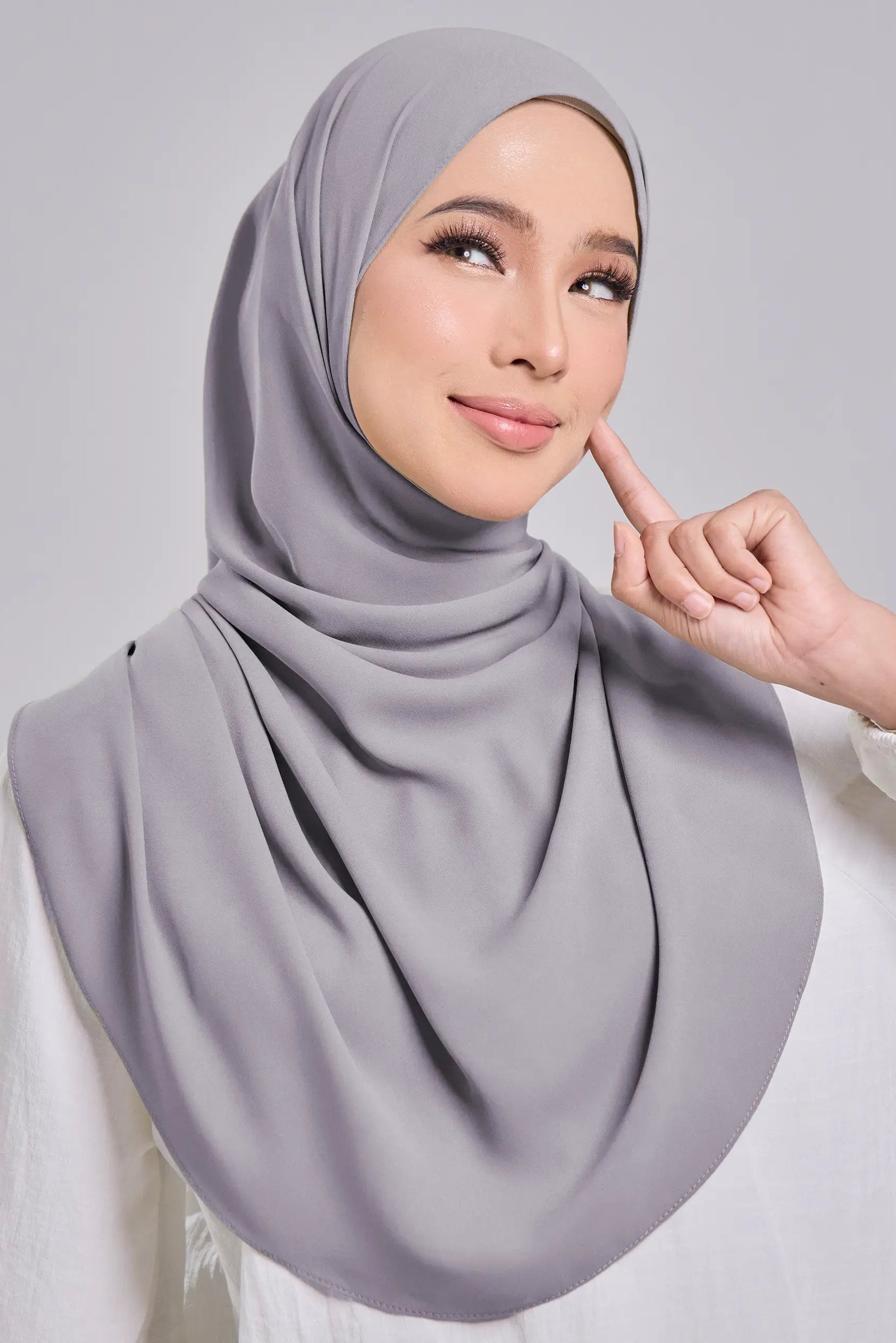 Woman wearing a gray hijab against a plain background