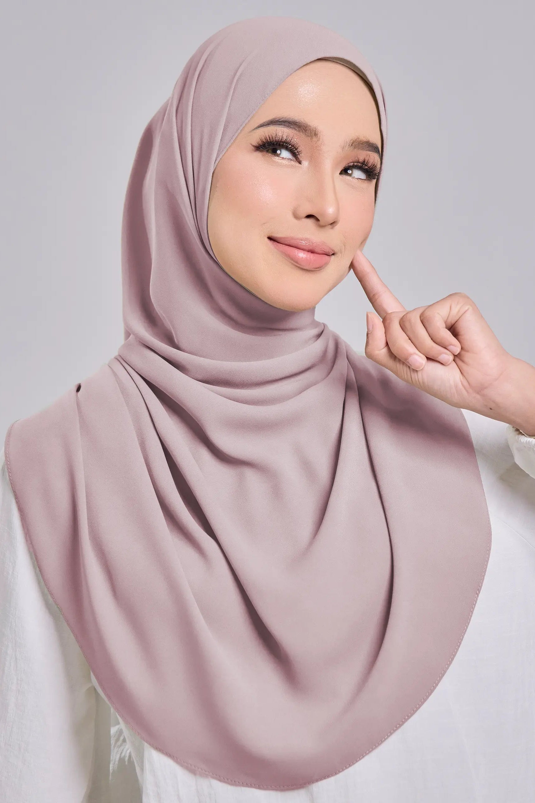Woman wearing a pink hijab against a gray background