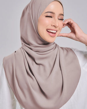 Woman wearing a beige hijab against a plain background