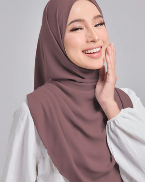 Woman wearing a brown hijab and white shirt on a gray background