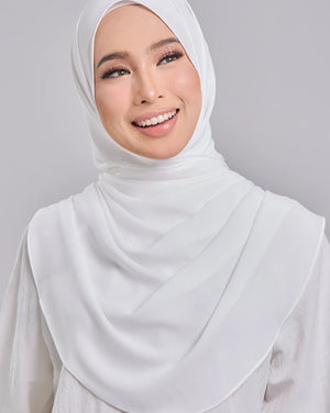 Woman wearing a white hijab and white outfit against a gray background