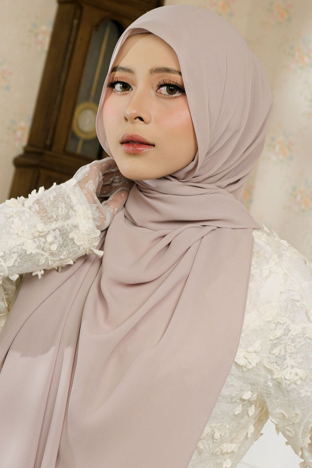 Woman wearing a beige hijab with a decorative background