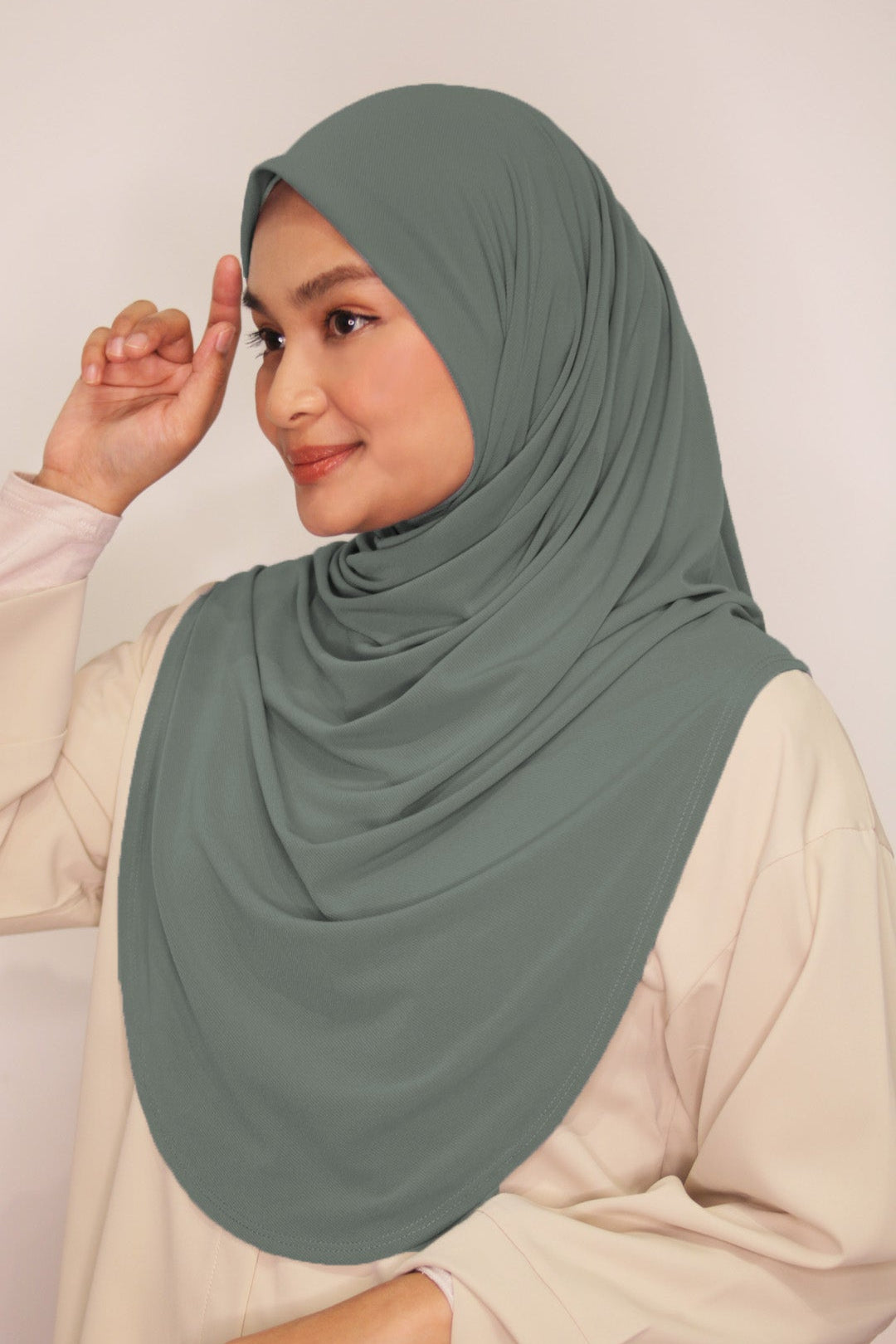Woman wearing a green hijab against a plain background