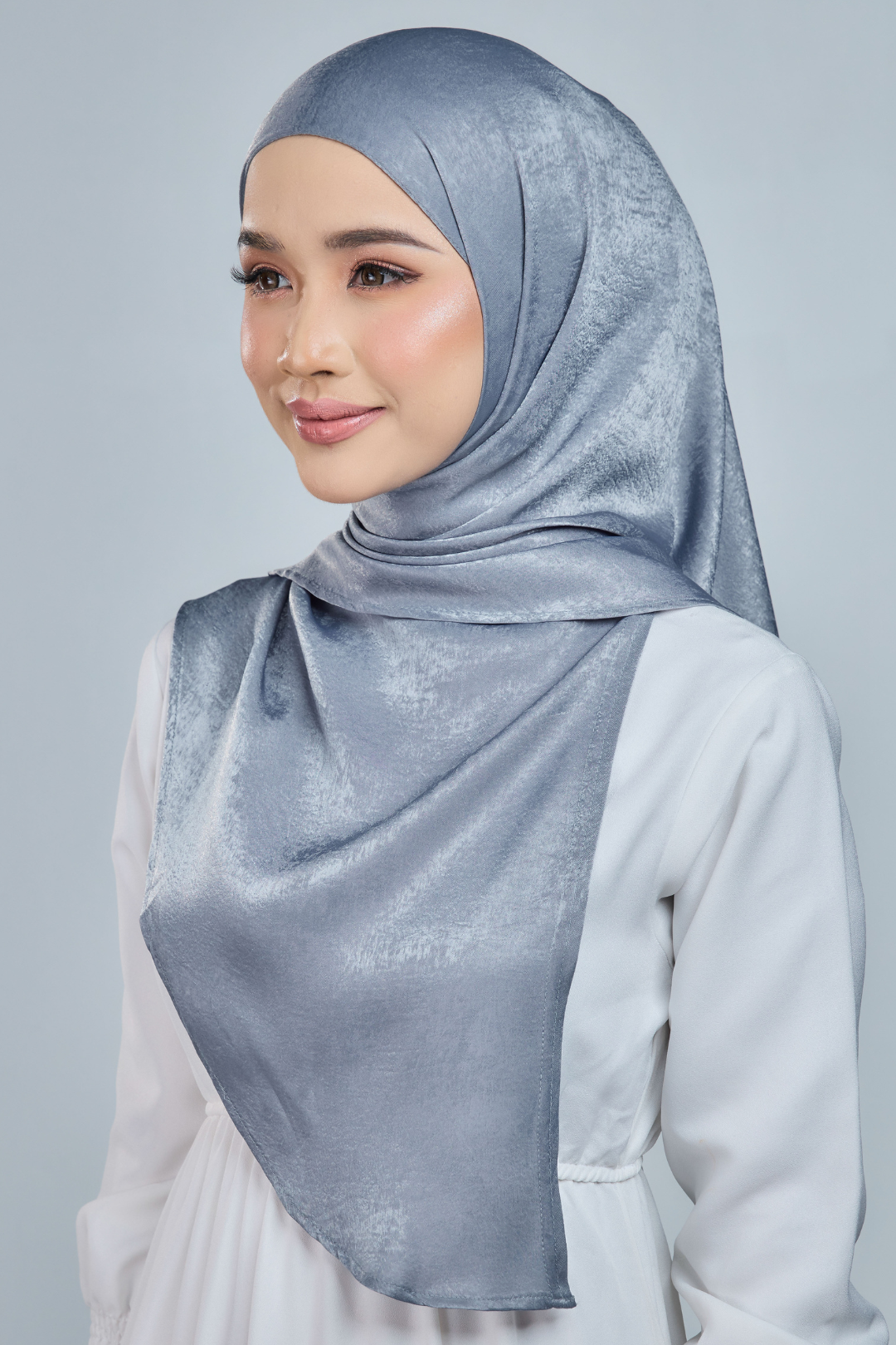 A person wearing a red half moon shaped shawl made of velvet satin with an adjustable tie back band.