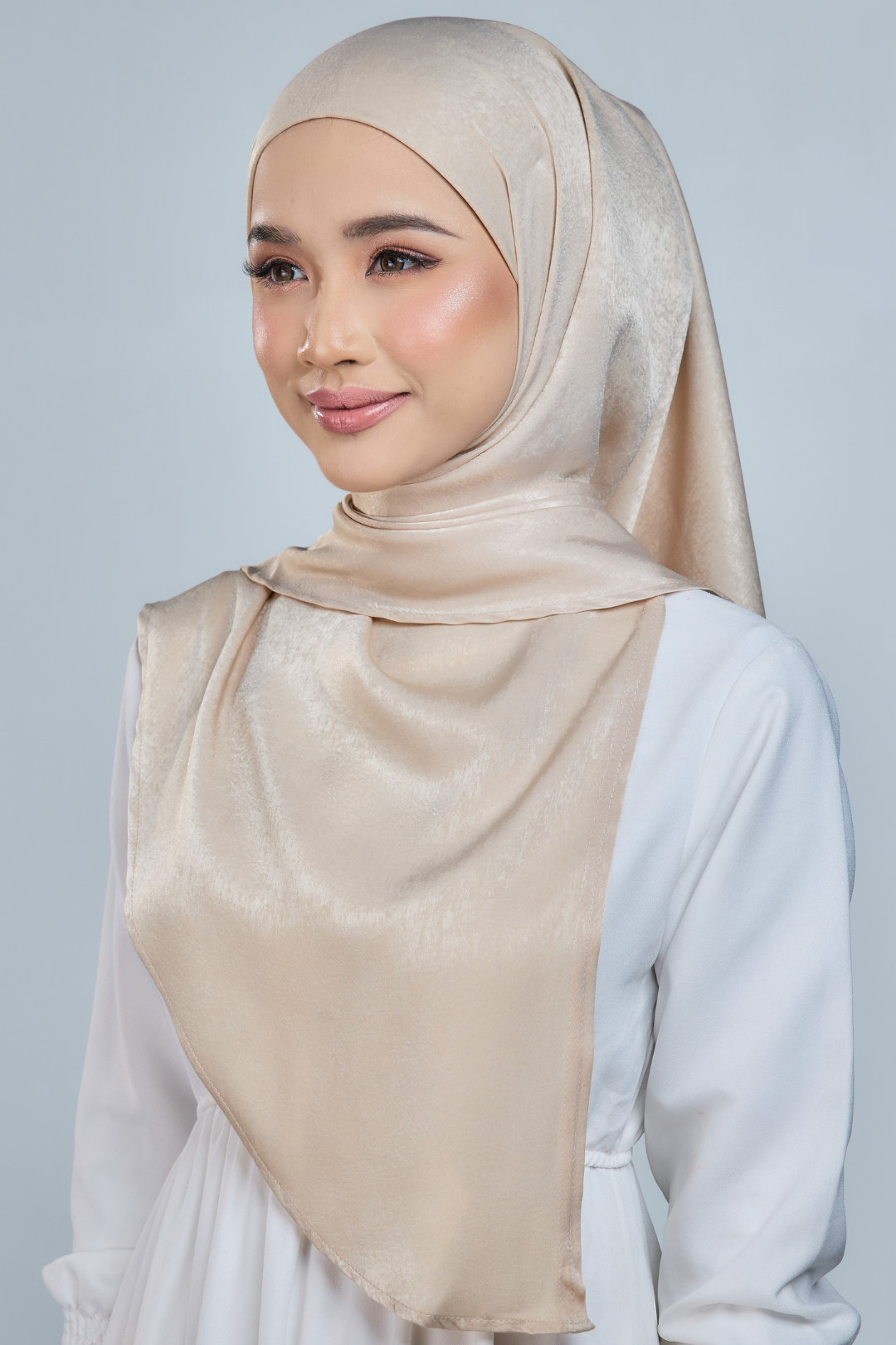 A person wearing a red half moon shaped shawl made of velvet satin with an adjustable tie back band.