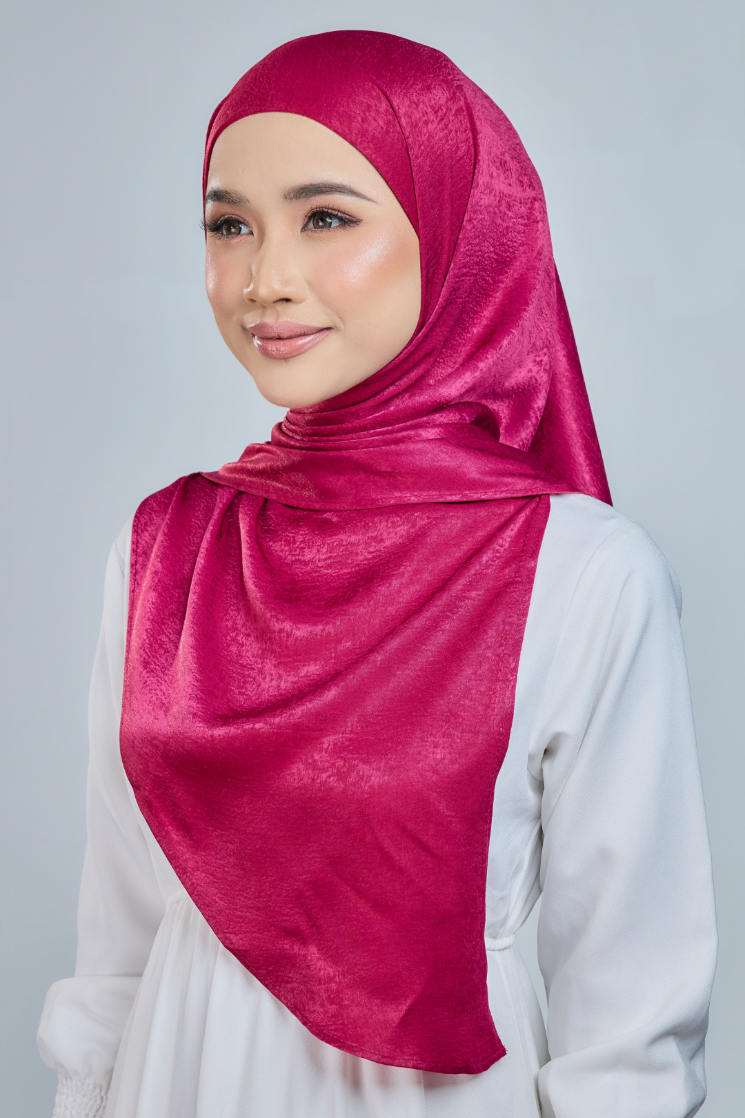 A person wearing a red half moon shaped shawl made of velvet satin with an adjustable tie back band.