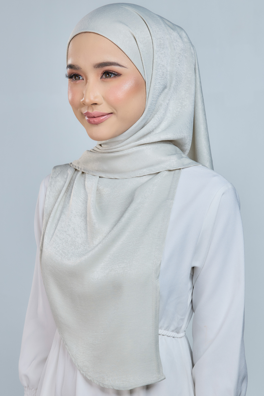 A person wearing a red half moon shaped shawl made of velvet satin with an adjustable tie back band.