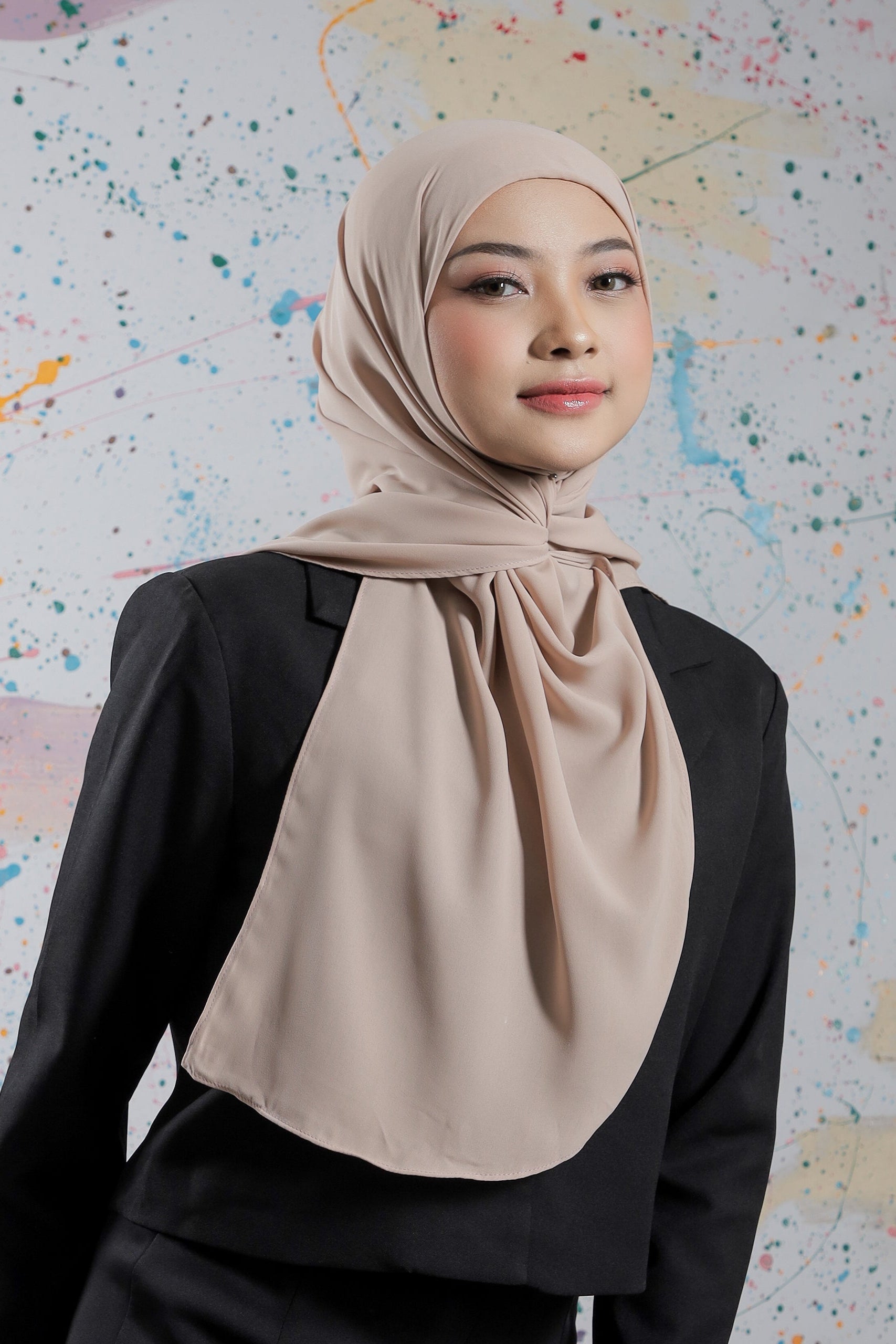 Woman wearing a beige hijab against a colorful abstract background