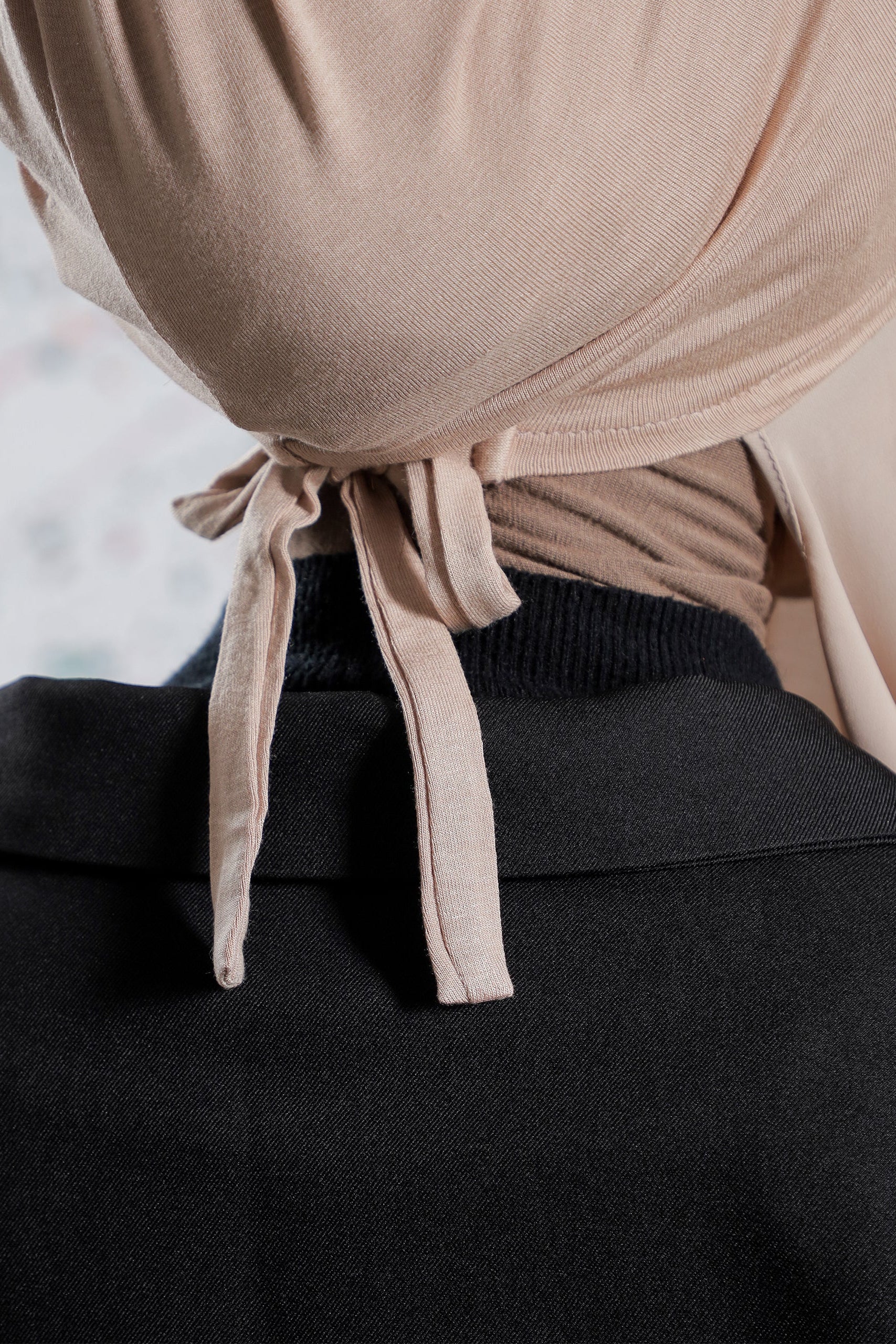 Close-up of a beige top with a tie detail on a blurred background
