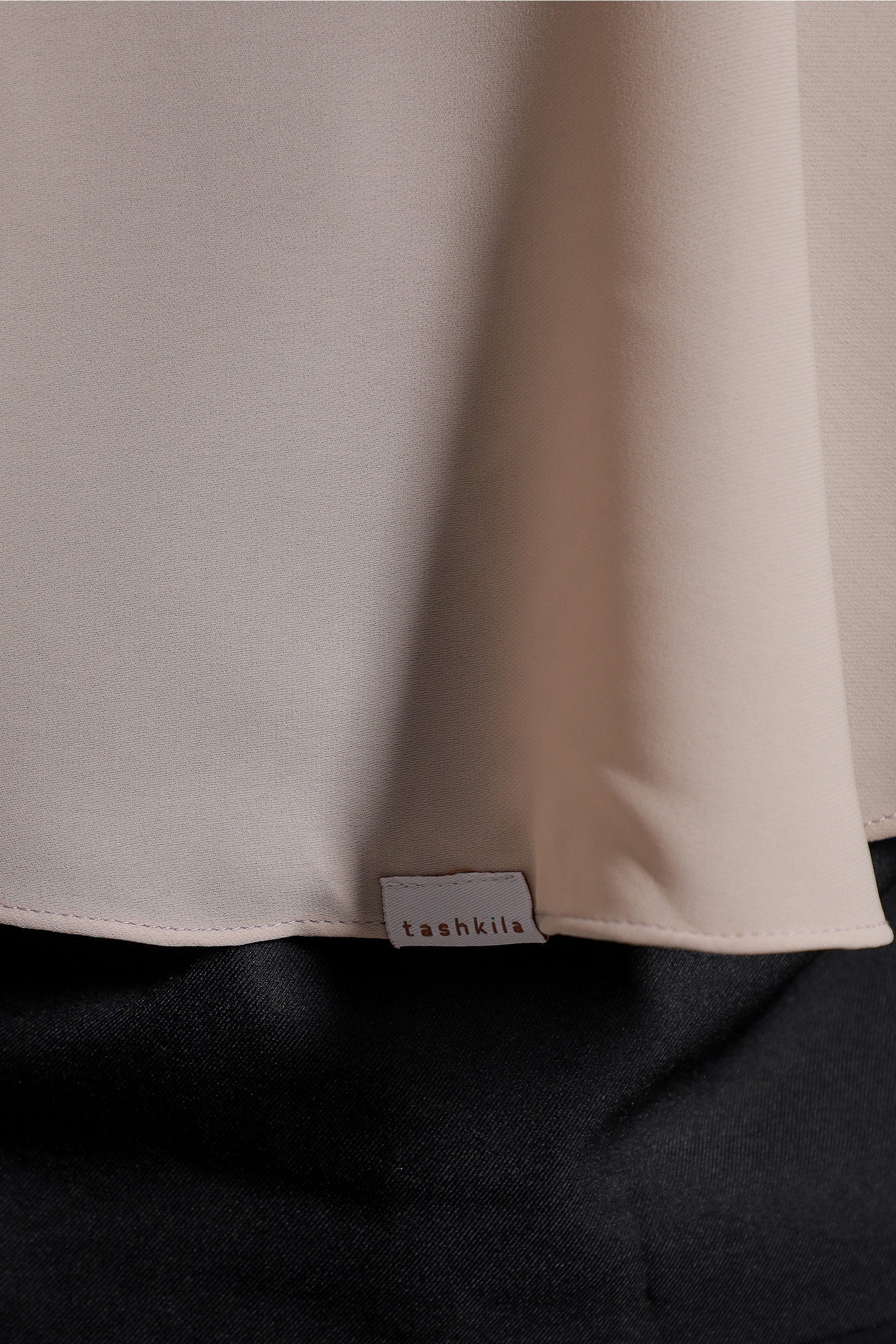 Close-up of a beige fabric with a brand label on a dark background
