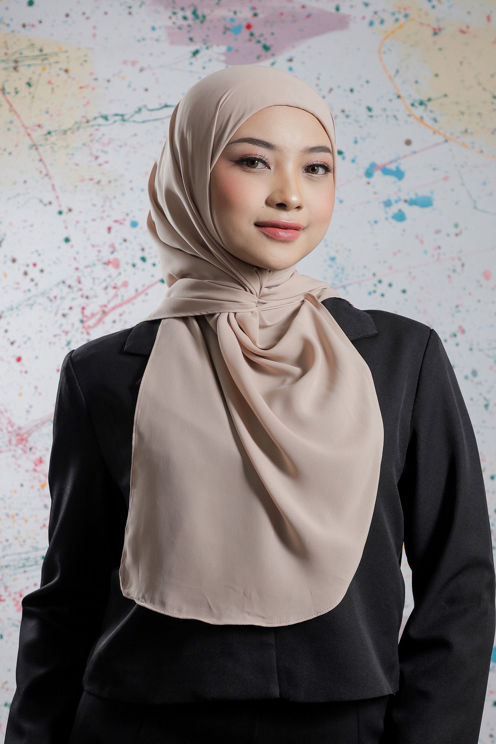 Woman wearing a beige hijab against a colorful abstract background