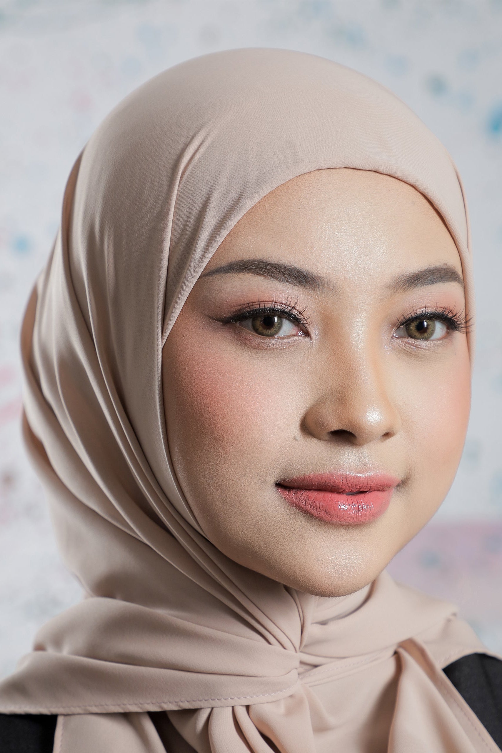 Woman wearing a beige hijab against a light background