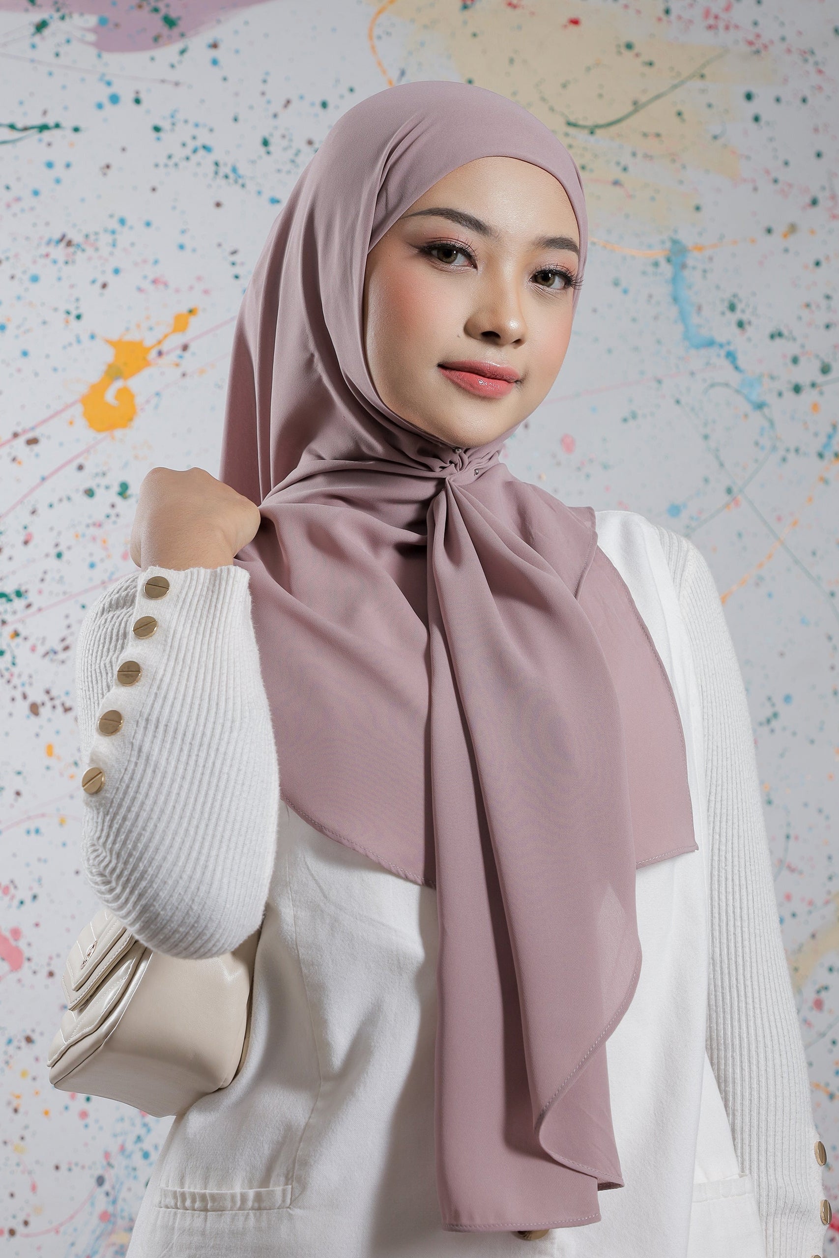 Woman wearing a light pink hijab against a colorful abstract background