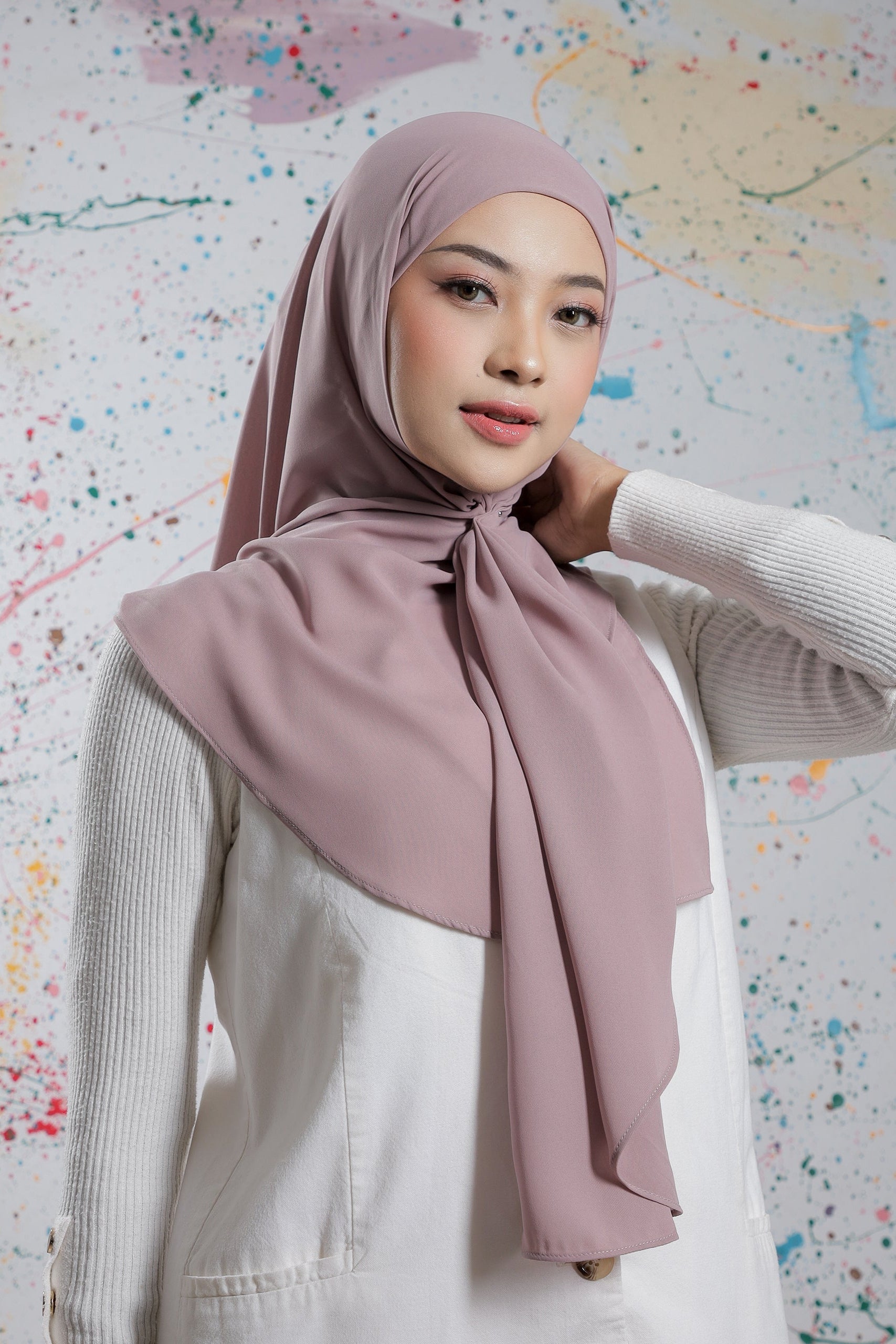 Woman wearing a pink hijab against a colorful abstract background