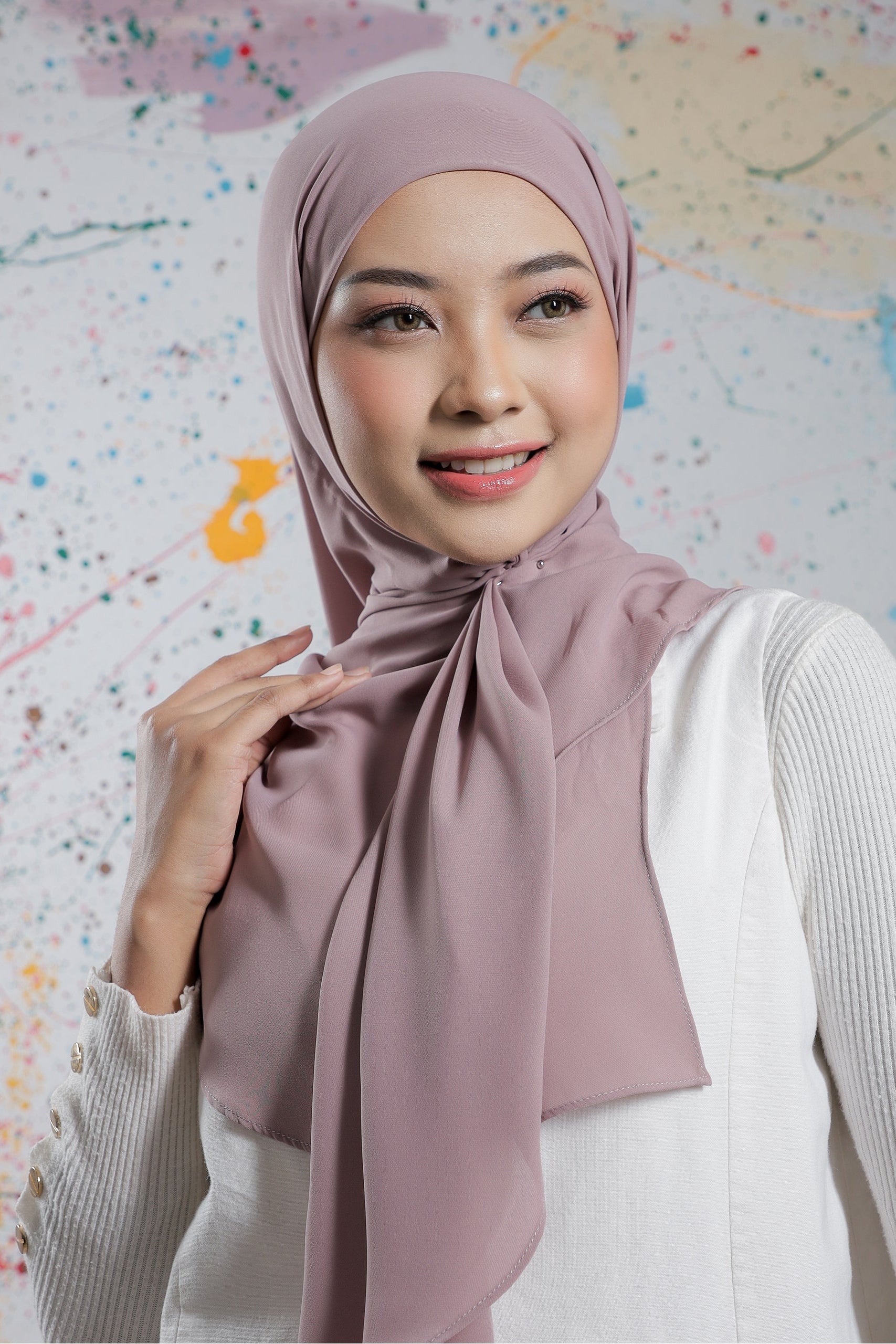 Woman wearing a pink hijab against a colorful abstract background