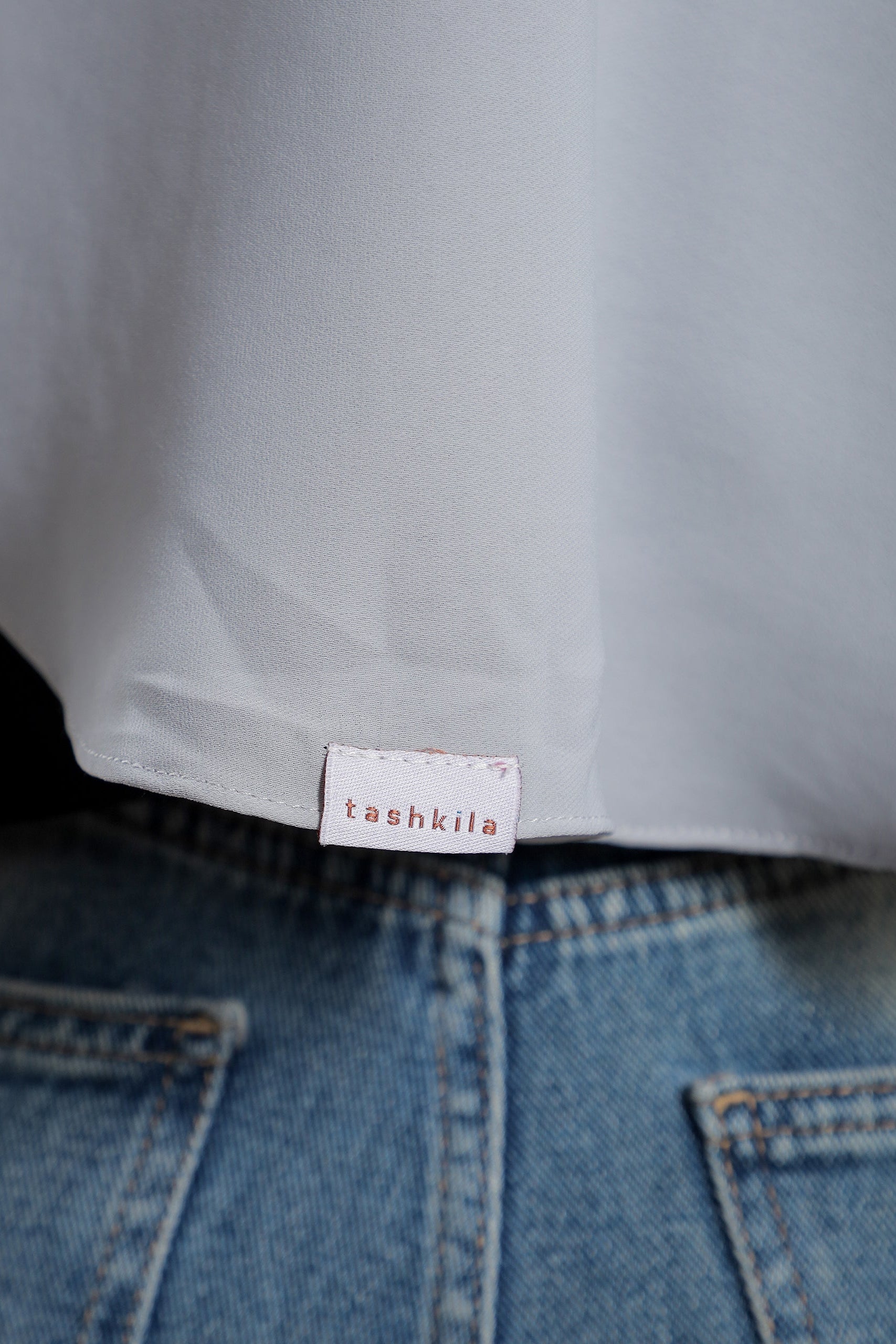 Close-up of a label on a garment with 'tashkila' branding.