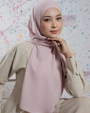 Woman wearing a light pink hijab and beige outfit against a colorful abstract background