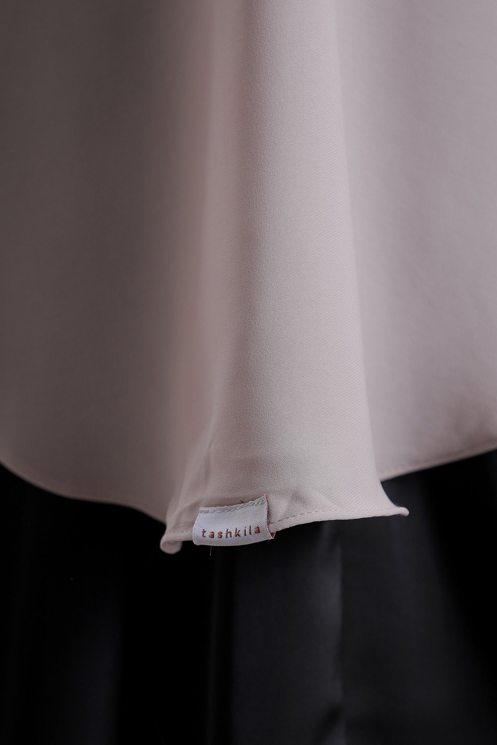 Close-up of a beige fabric with a brand label on a dark background