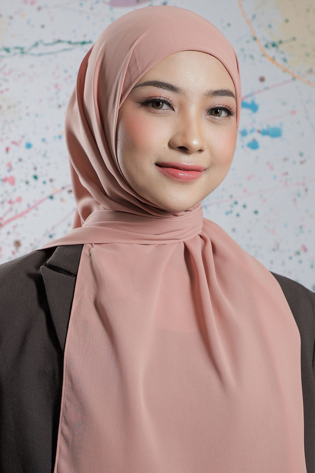 Woman wearing a pink hijab against a colorful abstract background