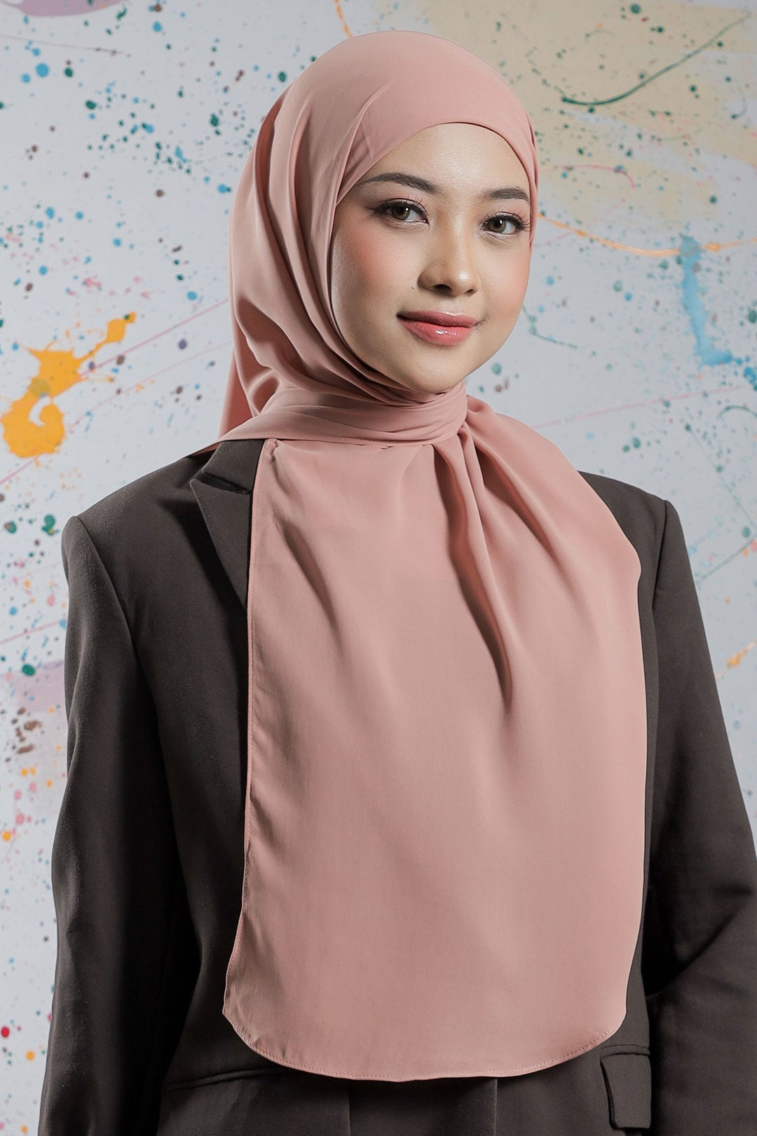 Woman wearing a pink hijab against a colorful abstract background