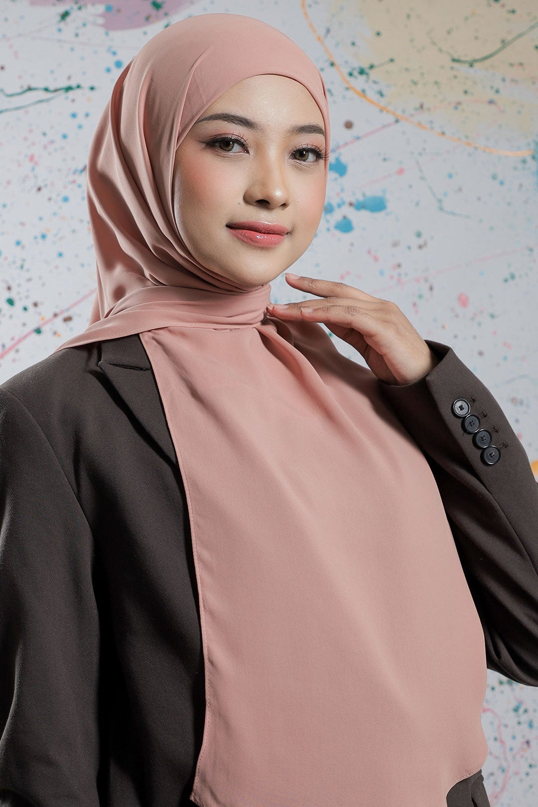 Woman wearing a pink hijab against a colorful abstract background
