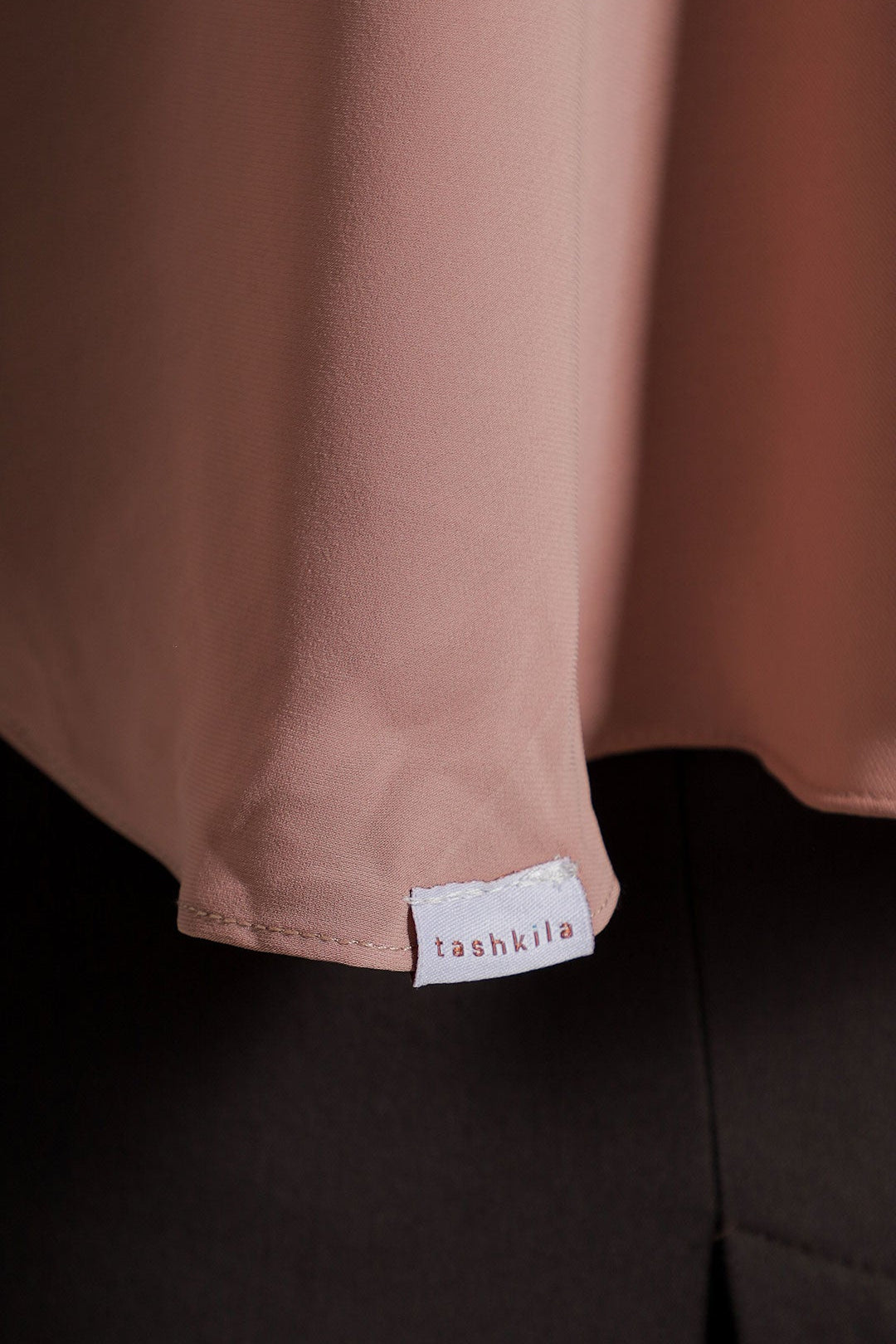 Close-up of a garment with a brand label on a plain background
