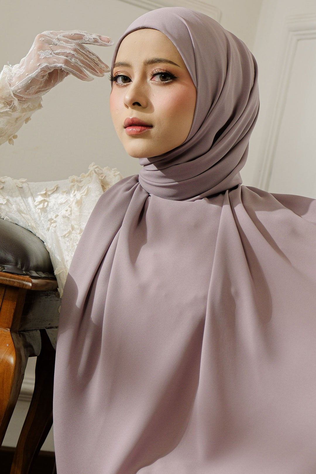 Woman wearing a light purple hijab and dress in an indoor setting