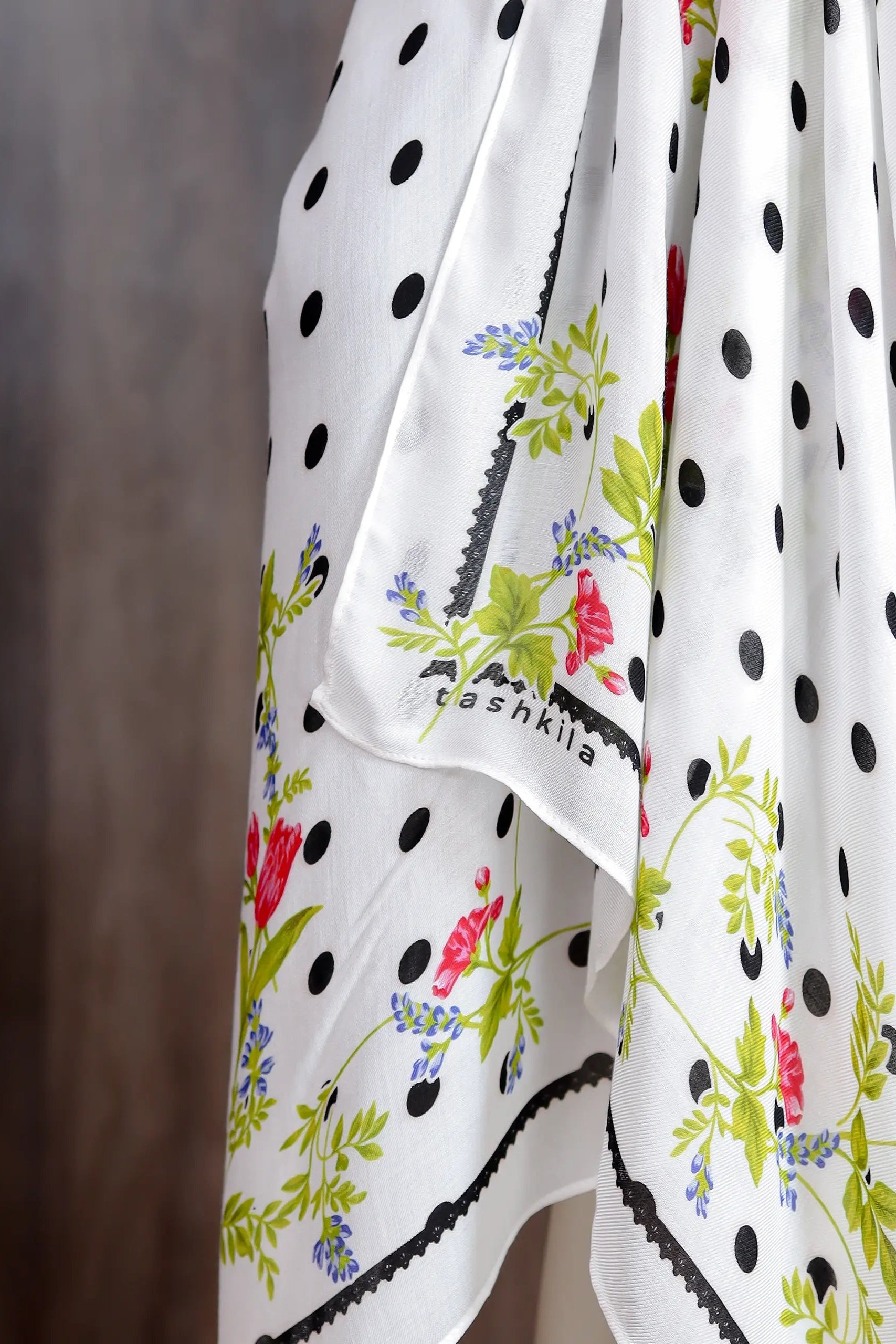 White scarf with black polka dots and colorful floral patterns, branded 'teshika'.