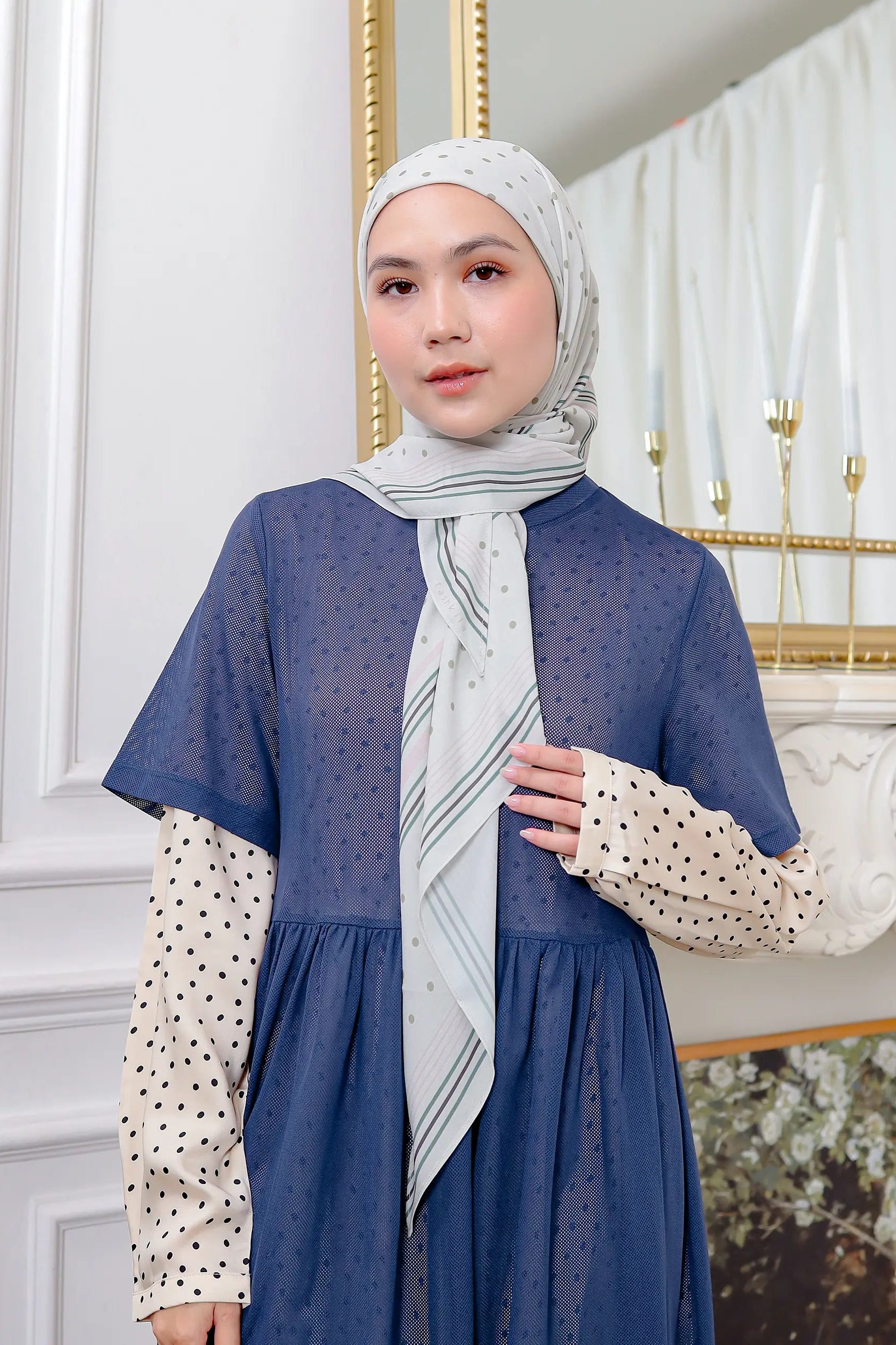 Woman wearing a blue dress with a patterned scarf in an elegant interior setting