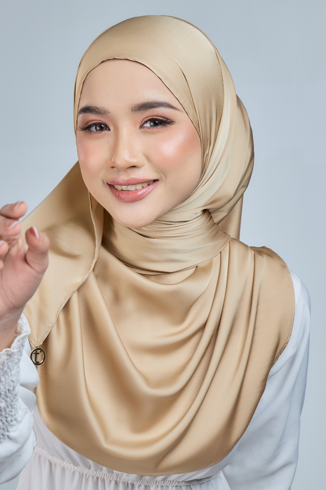 A woman wearing a champagne satin silk shawl draped over her shoulders, paired with a white outfit.
