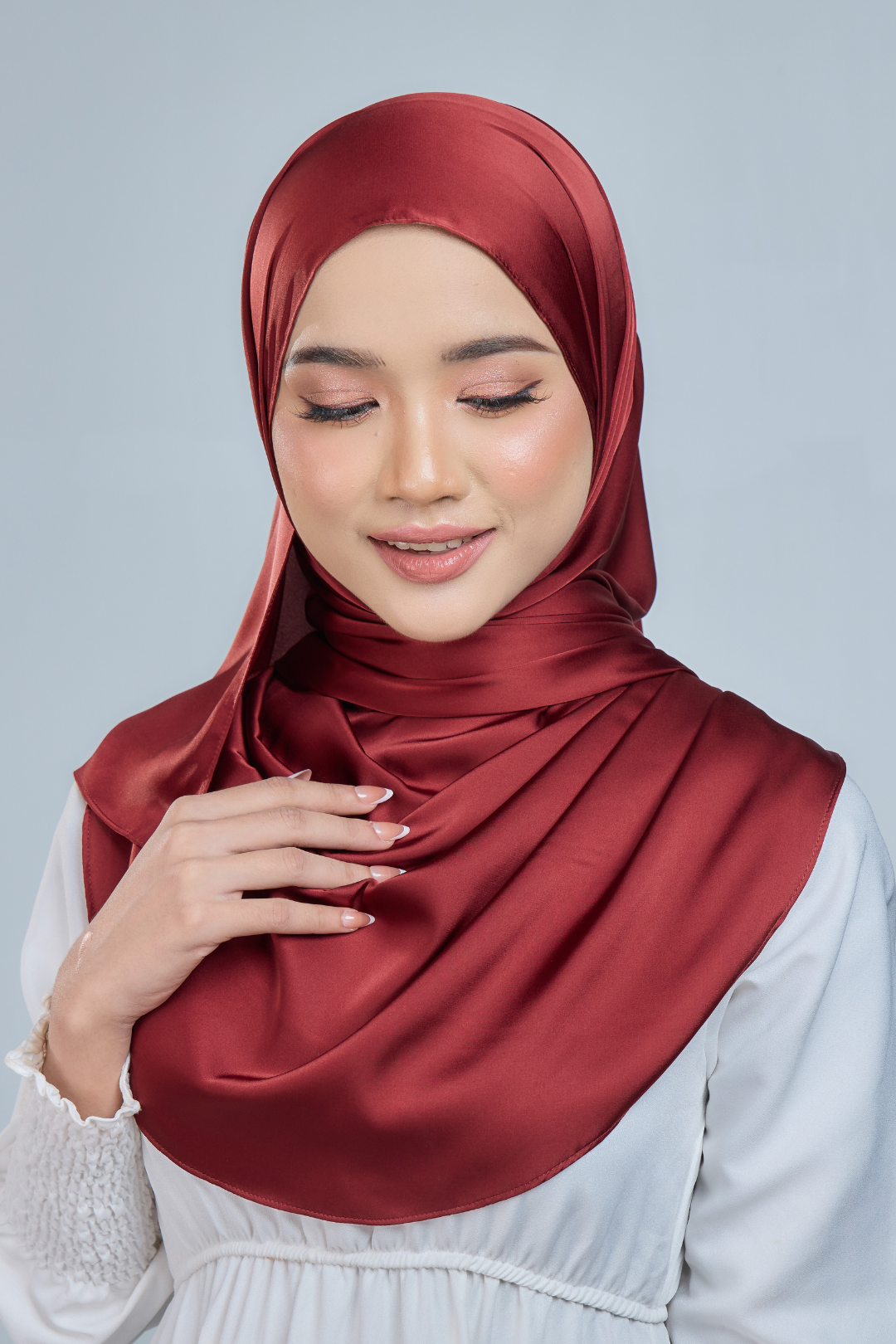 A woman wearing a maroon satin silk shawl draped over her shoulders, paired with a white outfit.