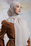 Woman wearing a hijab and brown outfit against a colorful abstract background