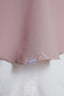 Close-up of a pink fabric with a visible brand label on a white background
