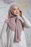 Woman wearing a light pink hijab against a colorful abstract background