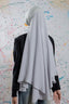 Person wearing a white hijab and black top against a colorful abstract wall.