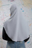 Person wearing a gray hijab with a colorful abstract pattern in the background