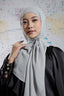 Woman wearing a light gray hijab against a world map background