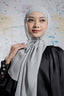 Woman wearing a light gray hijab and black outfit against a world map background