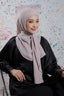Woman wearing a light pink hijab and black outfit against a colorful abstract background