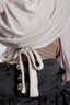 Close-up of a person wearing a beige hijab and black outfit with gold buttons.