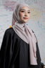 Woman wearing a light pink hijab and black outfit against a colorful abstract background