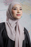 Woman wearing a light pink hijab and black outfit against a colorful abstract background
