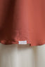 Close-up of a rust-colored fabric with a label on a light background